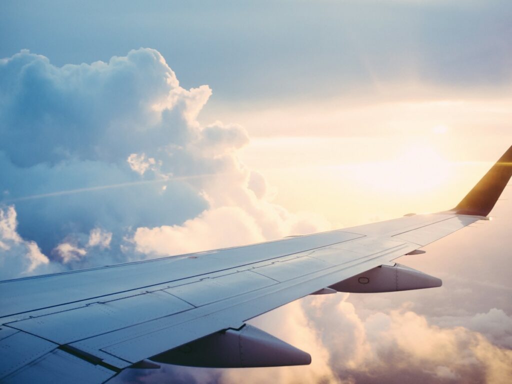 Airplane wing above the clouds in golden light