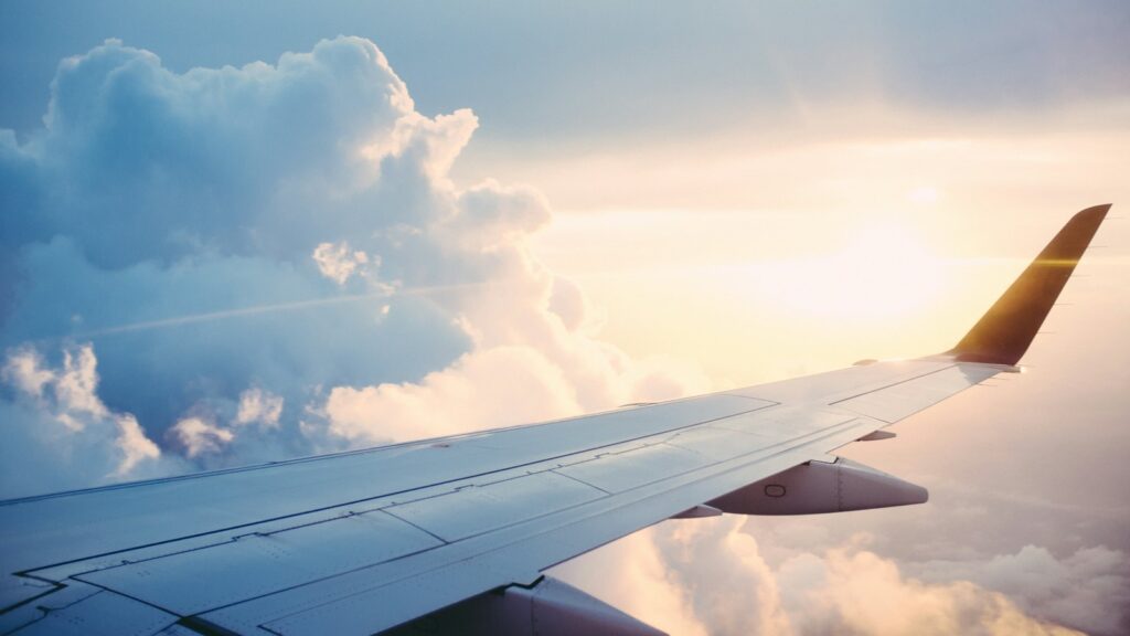 Airplane wing above the clouds in golden light