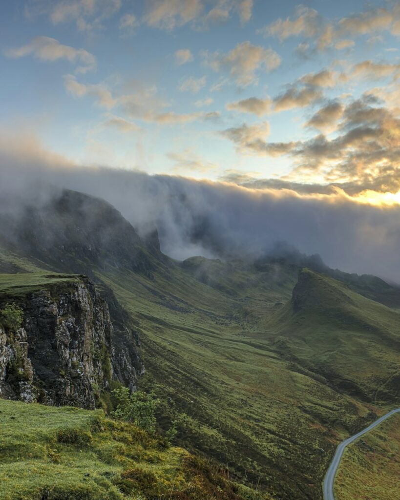 Green mountain valley with low clouds at sunset