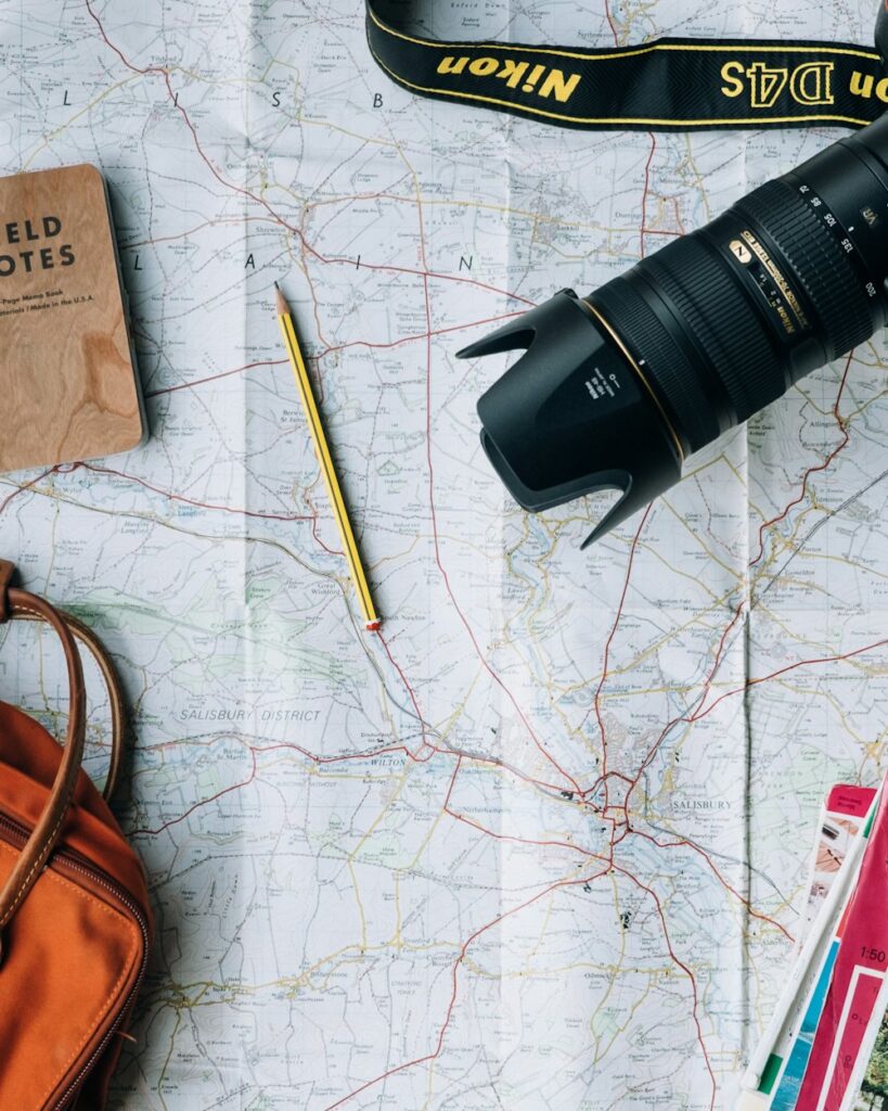 Paper map with a camera, a notebook and a pencil on a table