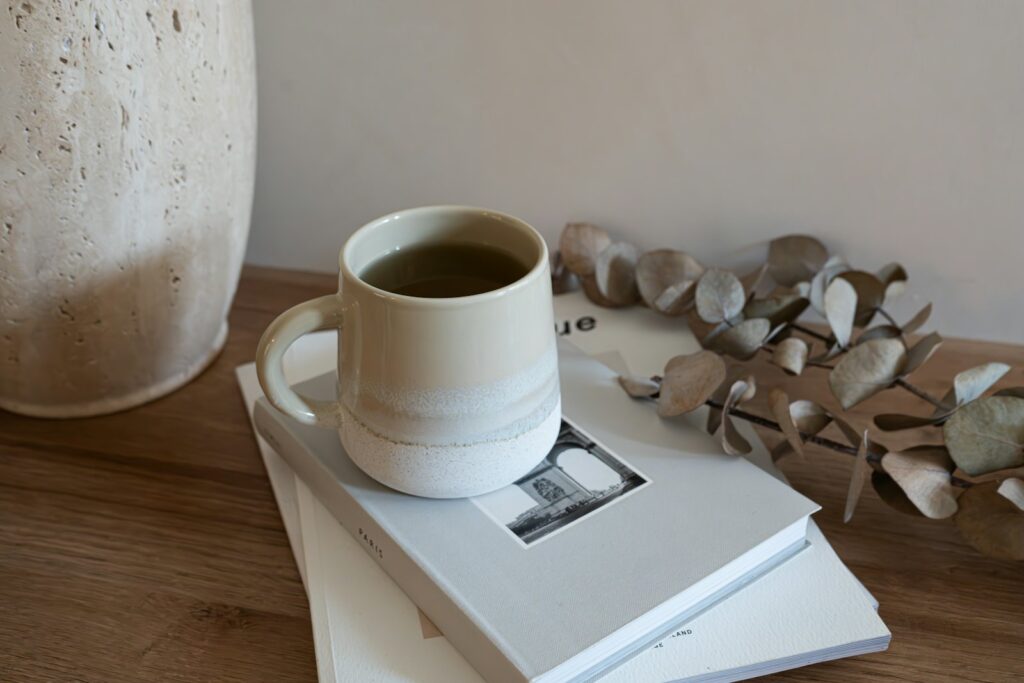 Cup on a stack of books with dried eucalyptus on a wooden table
